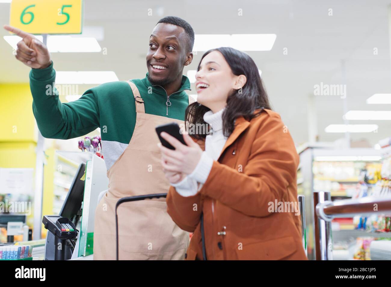 Männlicher Lebensmittelhändler hilft Kunden im Supermarkt Stockfoto