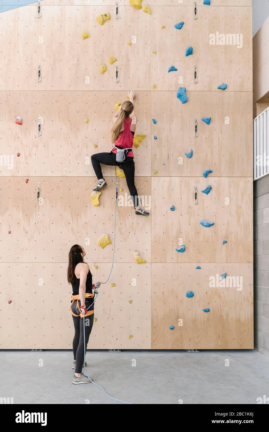 Frau mit Seilsicherungspartnerin an der Wand in der Kletterhalle Stockfoto