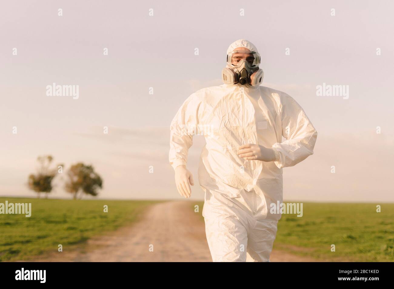 Mann mit Schutzanzug und Maske läuft auf dem Land Stockfoto