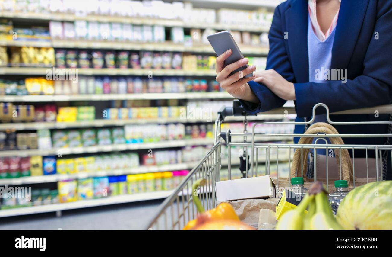 Frau mit Smart-Phone-Shopping im Supermarkt Stockfoto