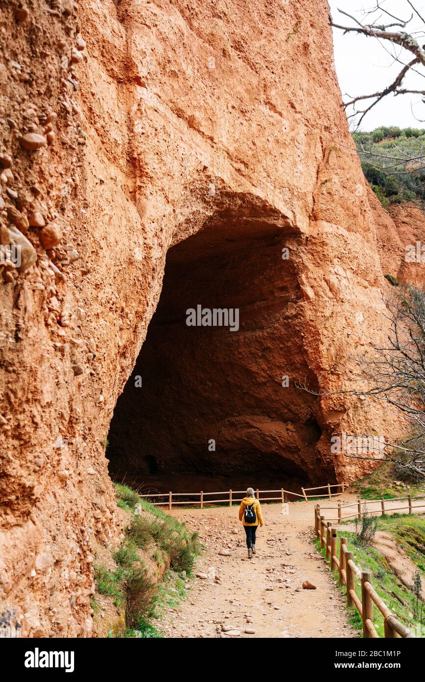 Wanderer am Eingang zu einem Tunnel, Mina de Oro Romana, ehemalige Goldmine, Las Medulas, Kastilien und Leon, Spanien Stockfoto