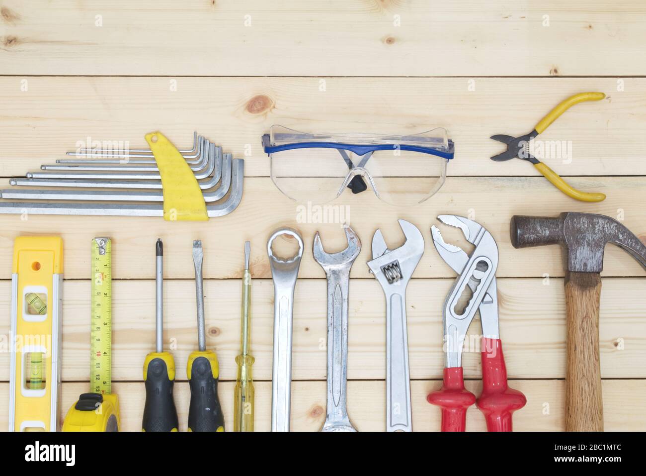 Werkzeugsatz auf Holztisch. Schraubendreher, Maßband, Hammer, Schraubenschlüssel und Sicherheitsglas. Technisches Werkzeugkonzept. Stockfoto