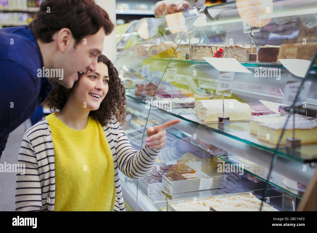 Ein Paar, das Desserts in der Vitrine der Bäckerei betrachtet Stockfoto
