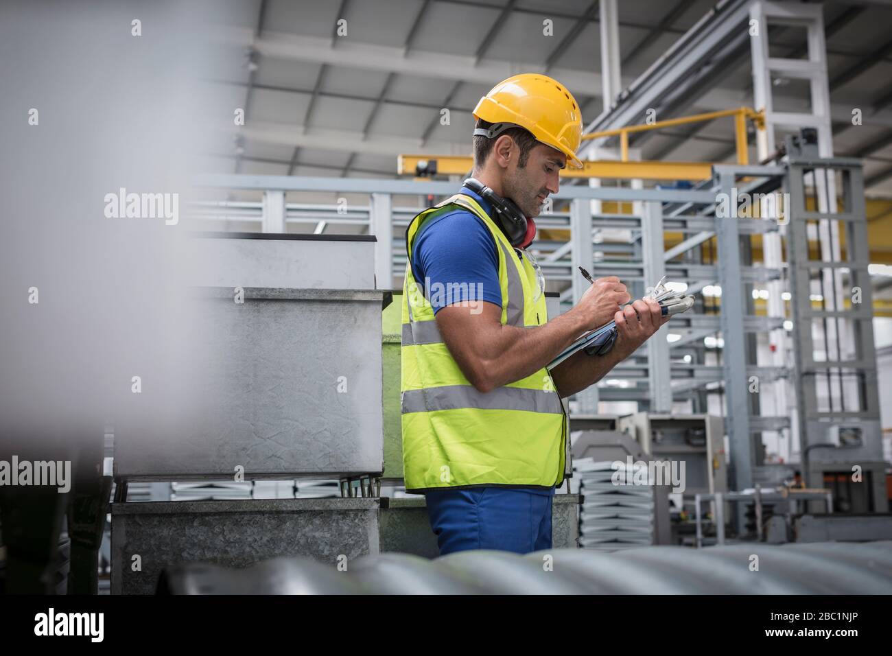 Männliche Führungskraft, die werkseitig in die Zwischenablage schreibt Stockfoto