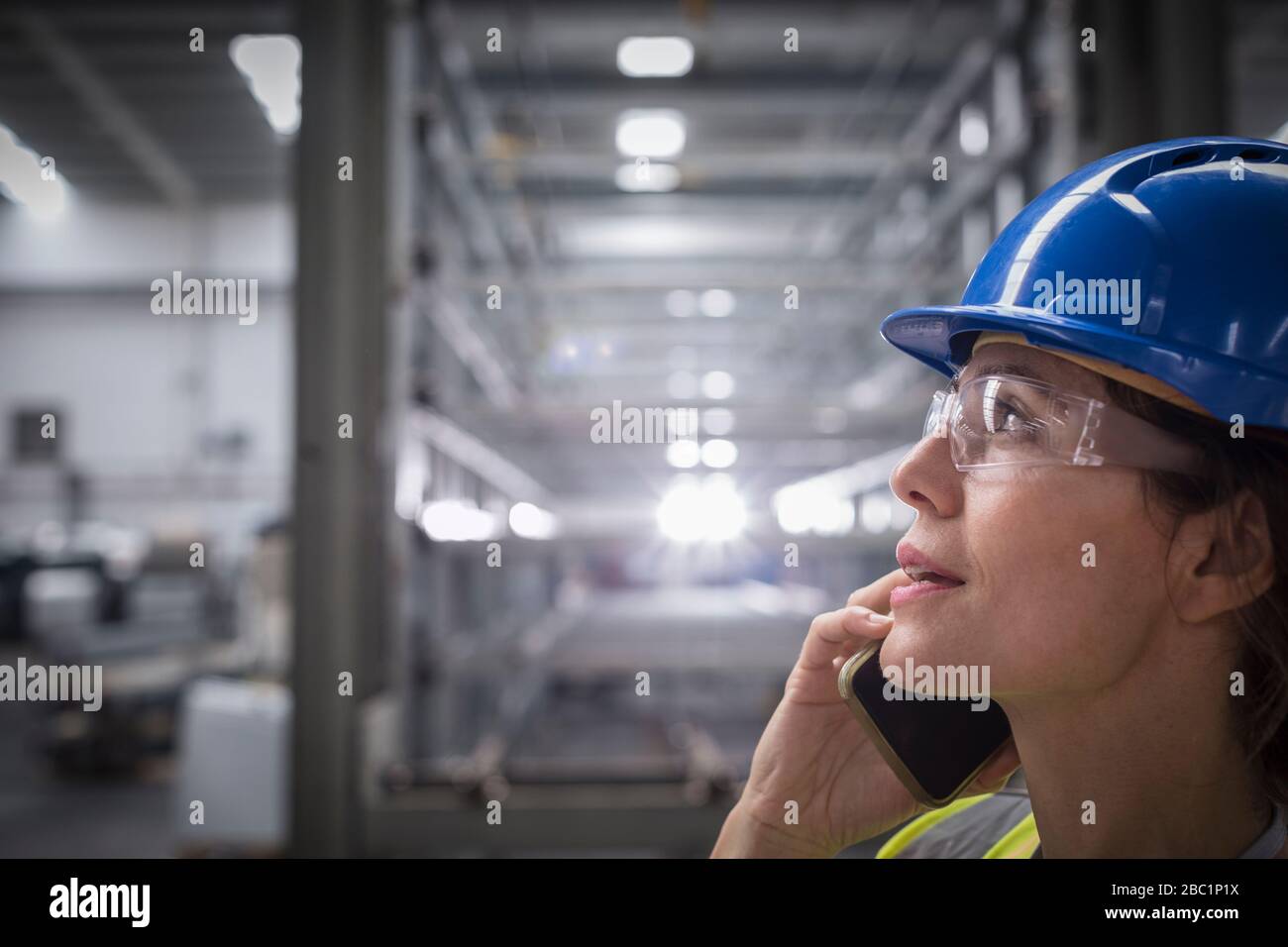 Arbeiter, die in der Fabrik auf dem Handy sprechen Stockfoto