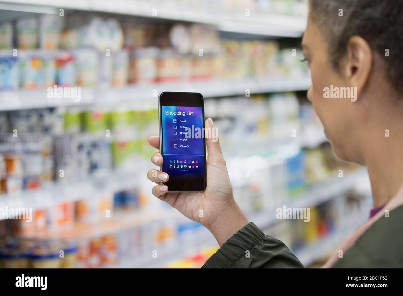 Frau mit digitaler Einkaufsliste auf Smartphone im Supermarkt Stockfoto