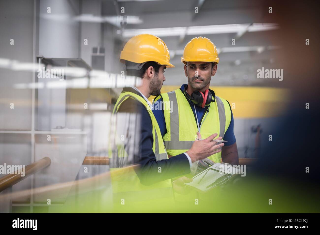 Männliche Führungskraft und Arbeiter mit Zwischenablage-Gespräch im Werk Stockfoto