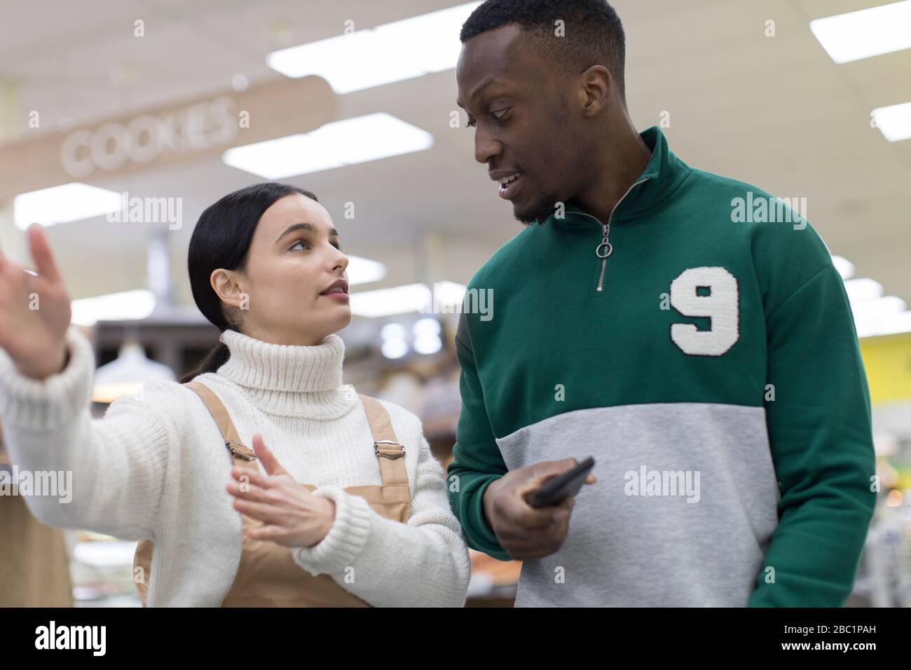 Weibliche Lebensmittelhändler helfen männlichen Kunden im Supermarkt Stockfoto