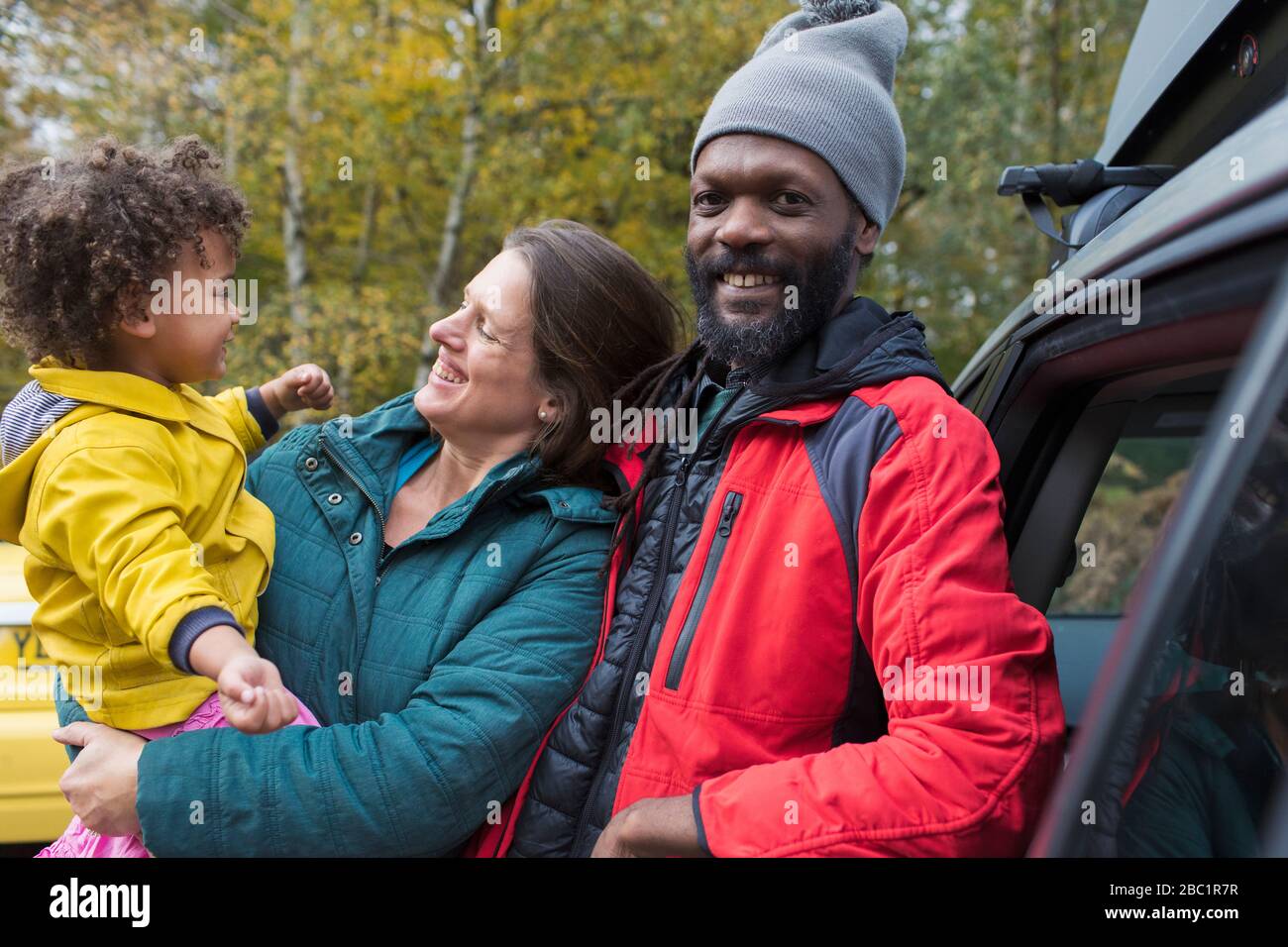 Portrait glückliche multiethnische Familie außerhalb des Autos Stockfoto