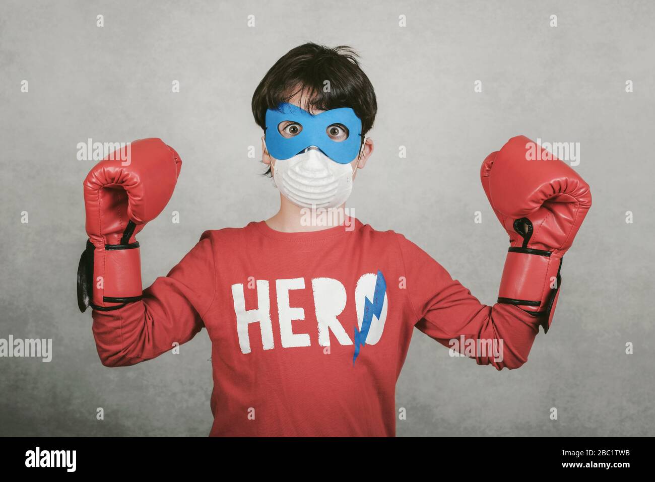 Coronavirus.child mit Maske für Coronavirus als Superheld über grauem Hintergrund gekleidet Stockfoto