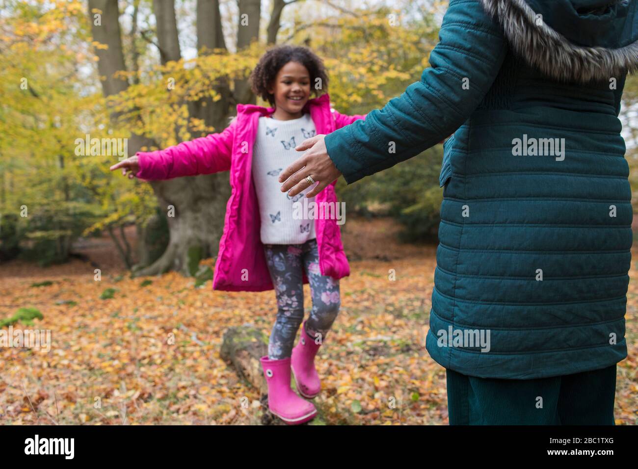 Fröhliche Mädchenbalance auf dem gefallenen Holzeinbauch im Herbstwald Stockfoto