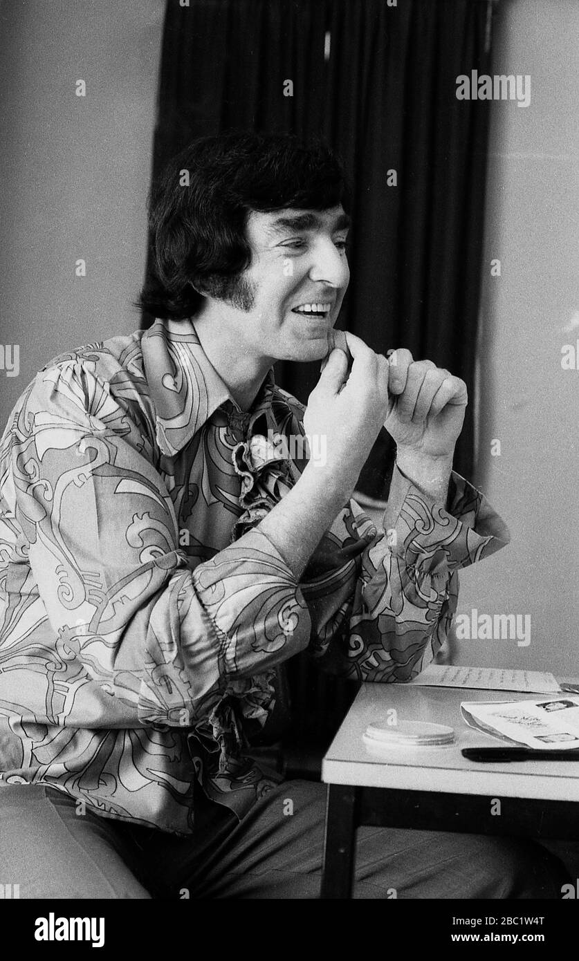 1970er Jahre, britischer Comedian und Entertainer von Kindern, Ken Goodwin, der Make-up vor einer Aufführung anwendet. Typischer 70er-Jahre-Look mit blumiger Hemd und langen Koteletten. Stockfoto