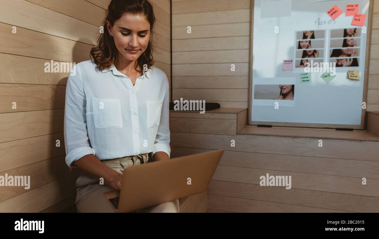 Geschäftsfrau mit Laptop im Büro. Geschäftsfrau mit mittlerem Erwachsenenalter, die im kreativen Büro an einem Laptop arbeitet. Stockfoto