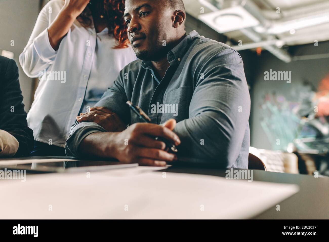 Gruppe verschiedener Geschäftsleute, die ein Meeting im Büro haben. Afrikanischer Mann sitzt in einem Treffen mit Kollegen im Konferenzraum. Stockfoto