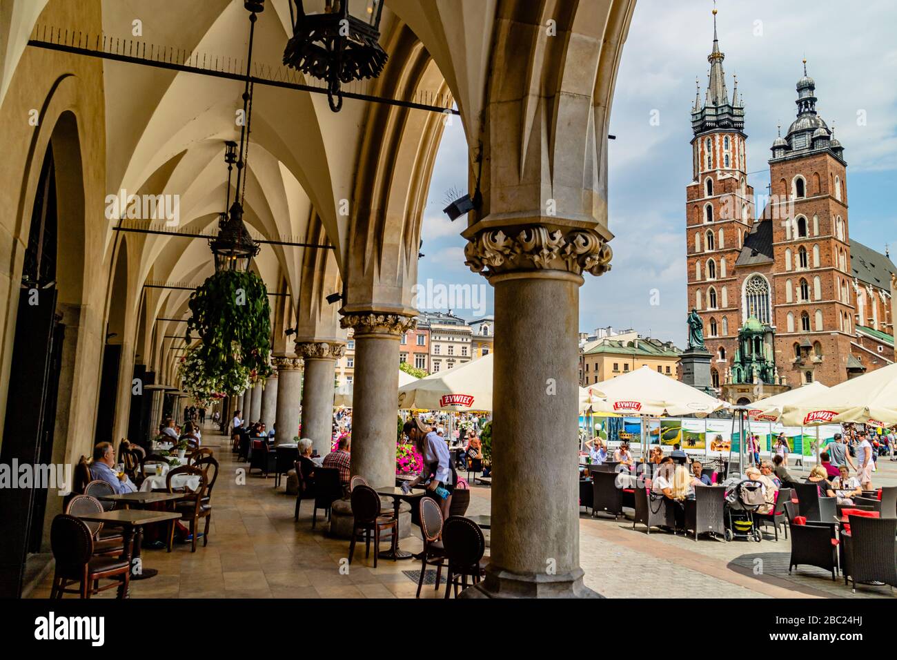Geschäftige Cafétische im Rynek Główny oder Hauptplatz, mit Blick auf die Basilika St. Mary's, im Stadtzentrum von Krakau, Polen. Juli 2017. Stockfoto