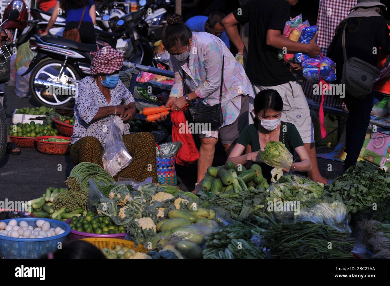 Kambodianischer Gemüseanbieter, der während der Coronavirus-Pandemie eine Maske mit maskierten Kunden trägt. Der Russische Markt Phnom Penh, Kambodscha. © Kraig Lieb Stockfoto
