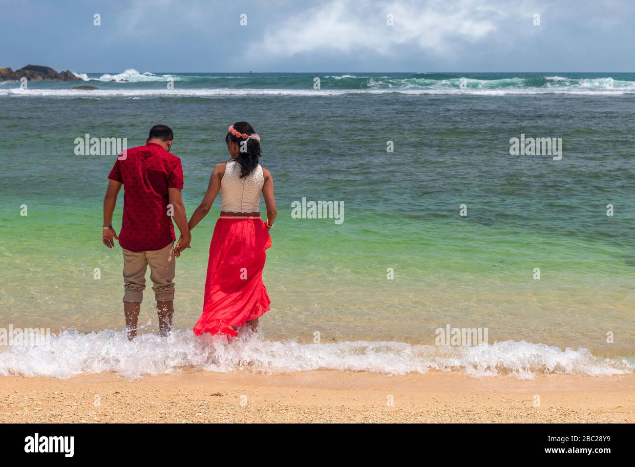Ein Flitterwochen-Paar hält die Hände, während sie im Indischen Ozean in Galle in Sri Lanka paddeln. Stockfoto