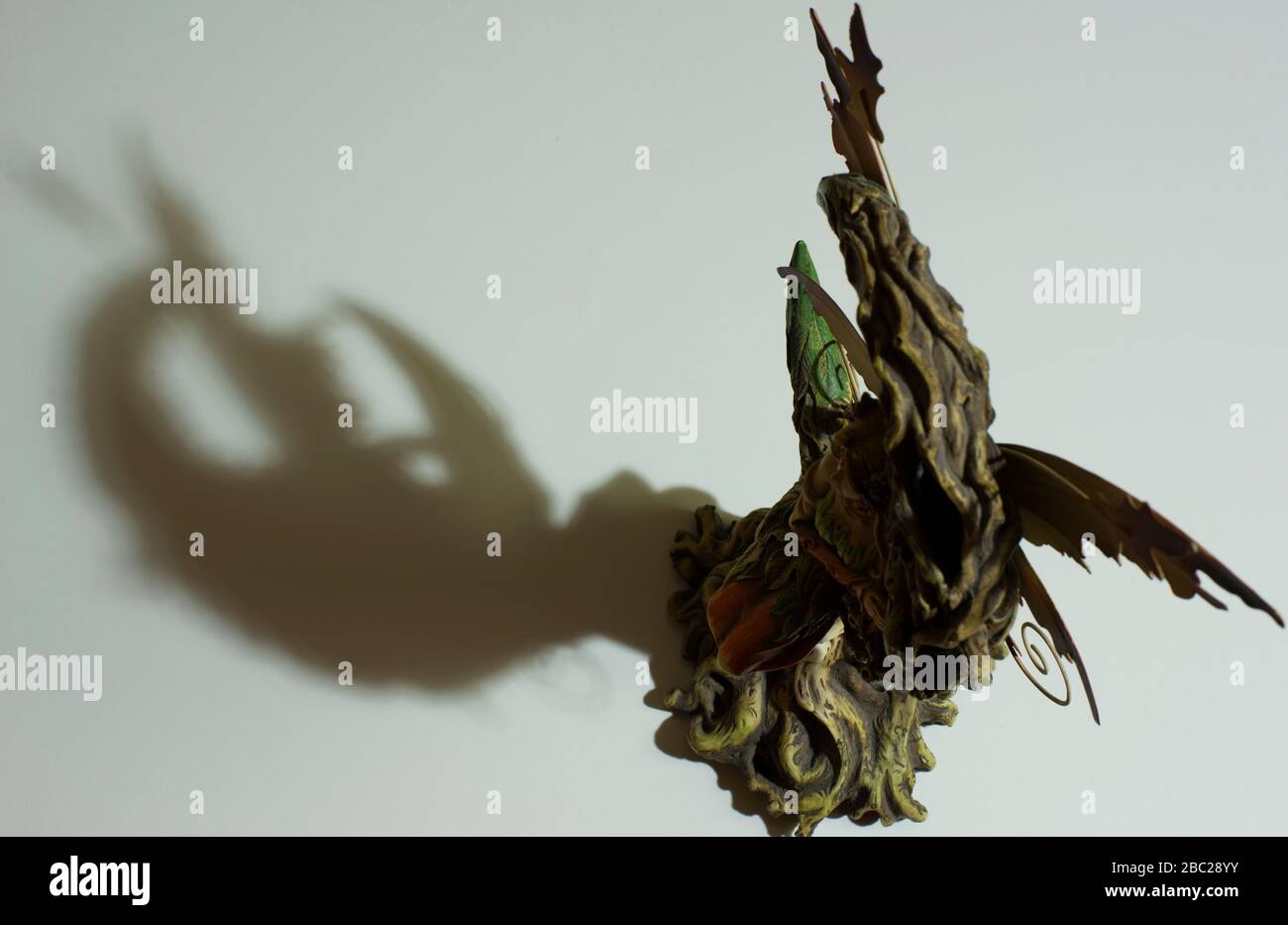 Fee Miniatur-Gießschatten auf weißem Tisch. Konzept: Fantasy, Minimalismus in der Fotografie. Stockfoto