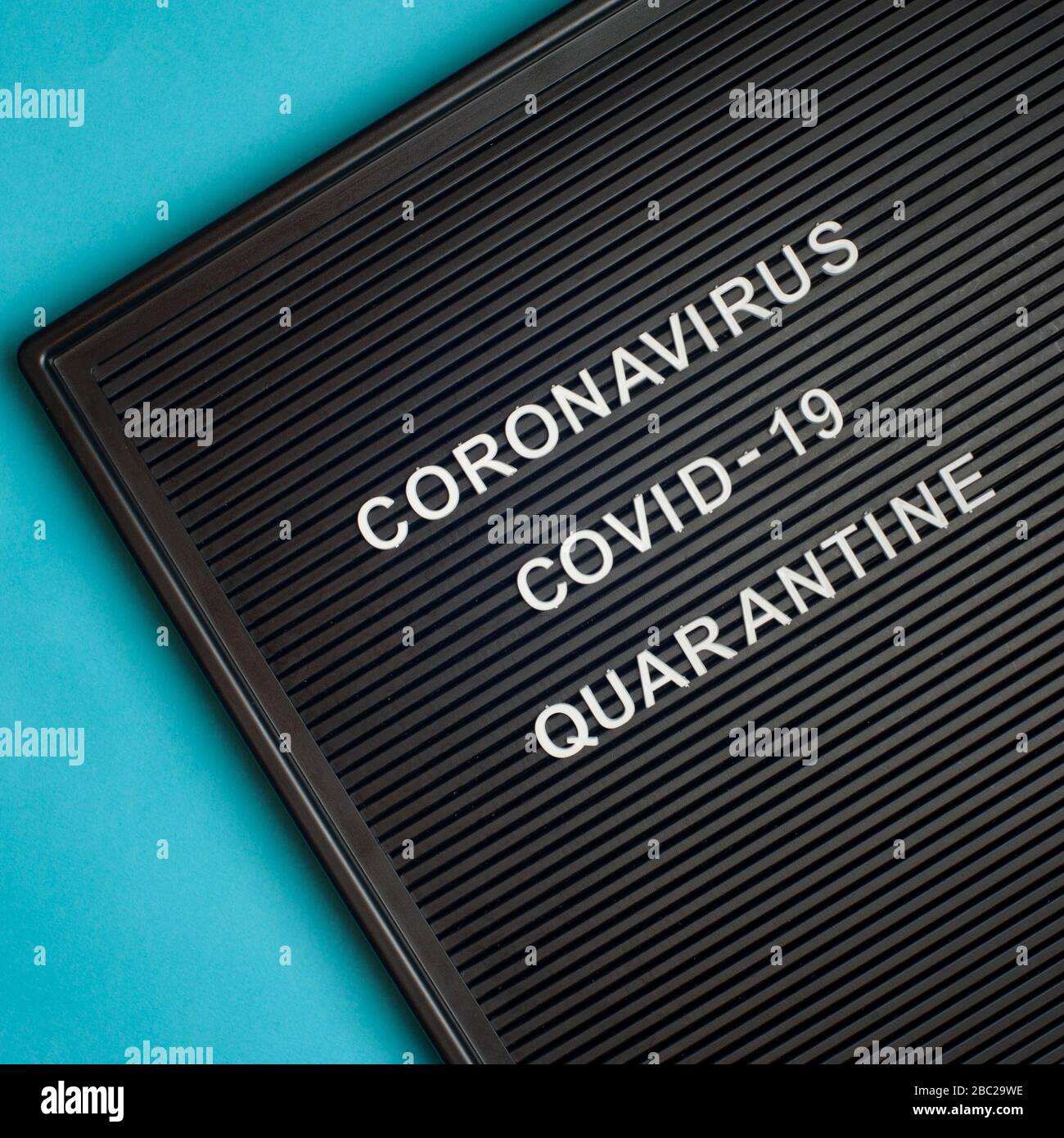 Coronavirus - COVID -19 - Quarantäne - Text auf schwarzem Briefbrett auf blauem Hintergrund. Stockfoto