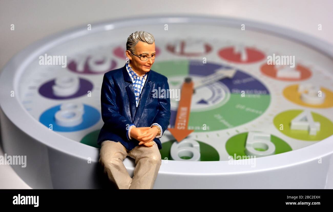 Miniatur Figur männlich Alter Rentner, sitzt auf einem Zifferblatt Uhr Stockfoto