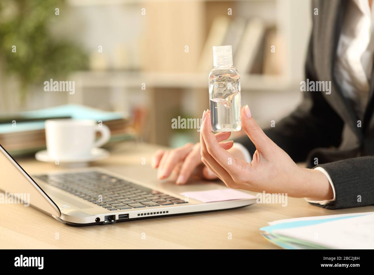 Nahaufnahme der Unternehmerin mit dem Laptop, auf dem Desinfektionsmittel auf einem Schreibtisch im Büro sitzt Stockfoto