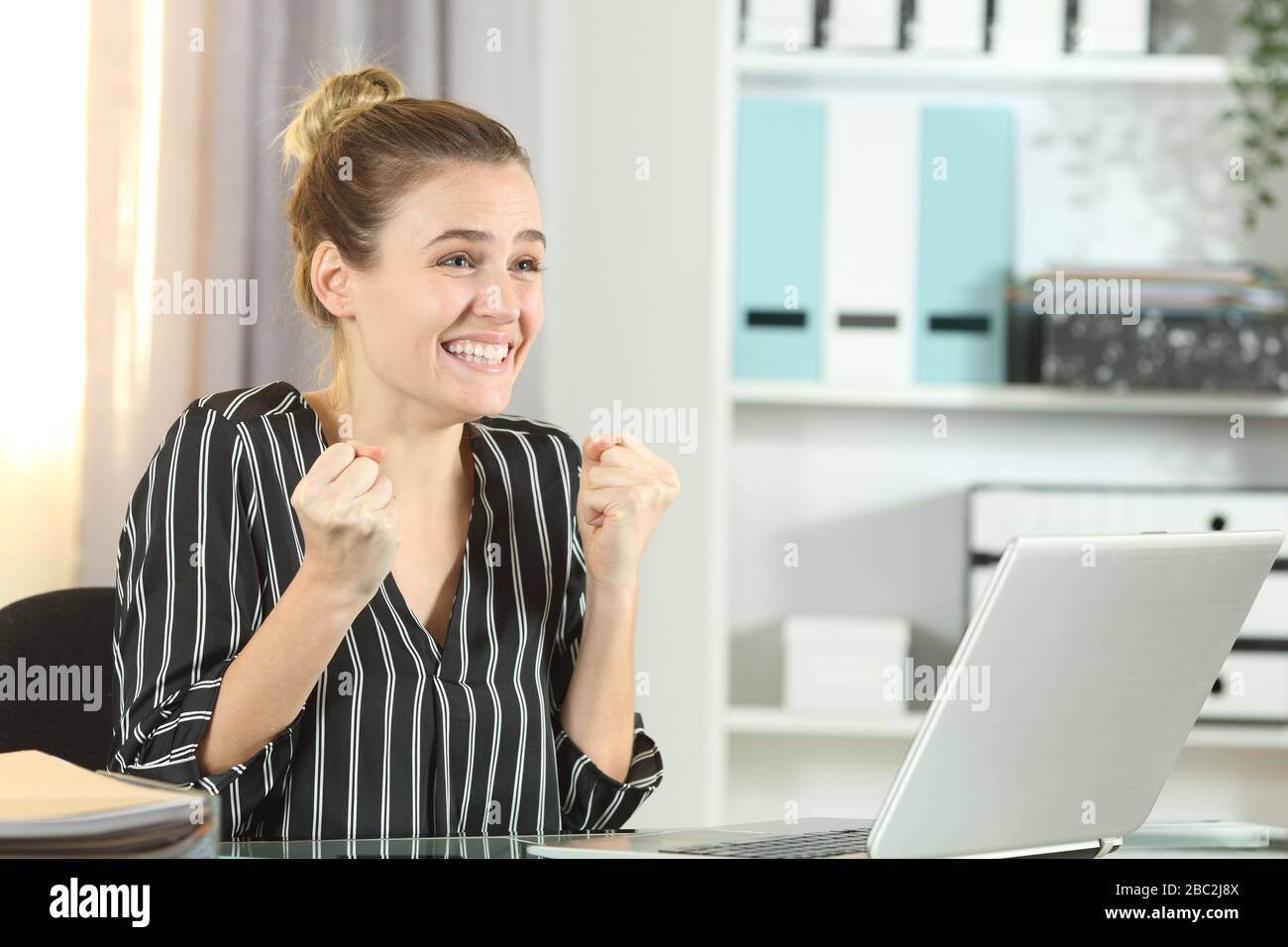 Aufgeregter Unternehmer, der gute Nachrichten auf einem Laptop feiert, der auf einem Schreibtisch im Büro stachelt Stockfoto