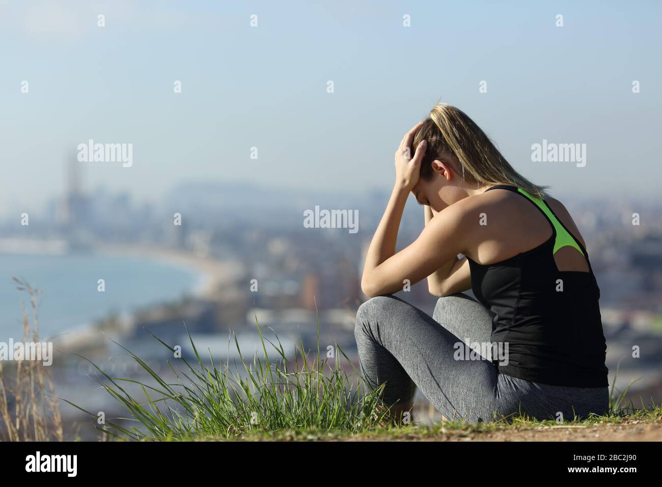 Frustrierte Läuferin sitzt im Freien und beschwert sich an einem sonnigen Tag in den Außenbezirken der Stadt Stockfoto