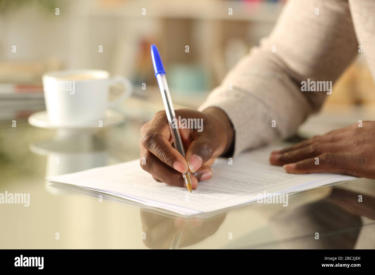 Nahaufnahme eines schwarzen Mannes, der das Formular auf einem Schreibtisch zu Hause ausfüllt Stockfoto