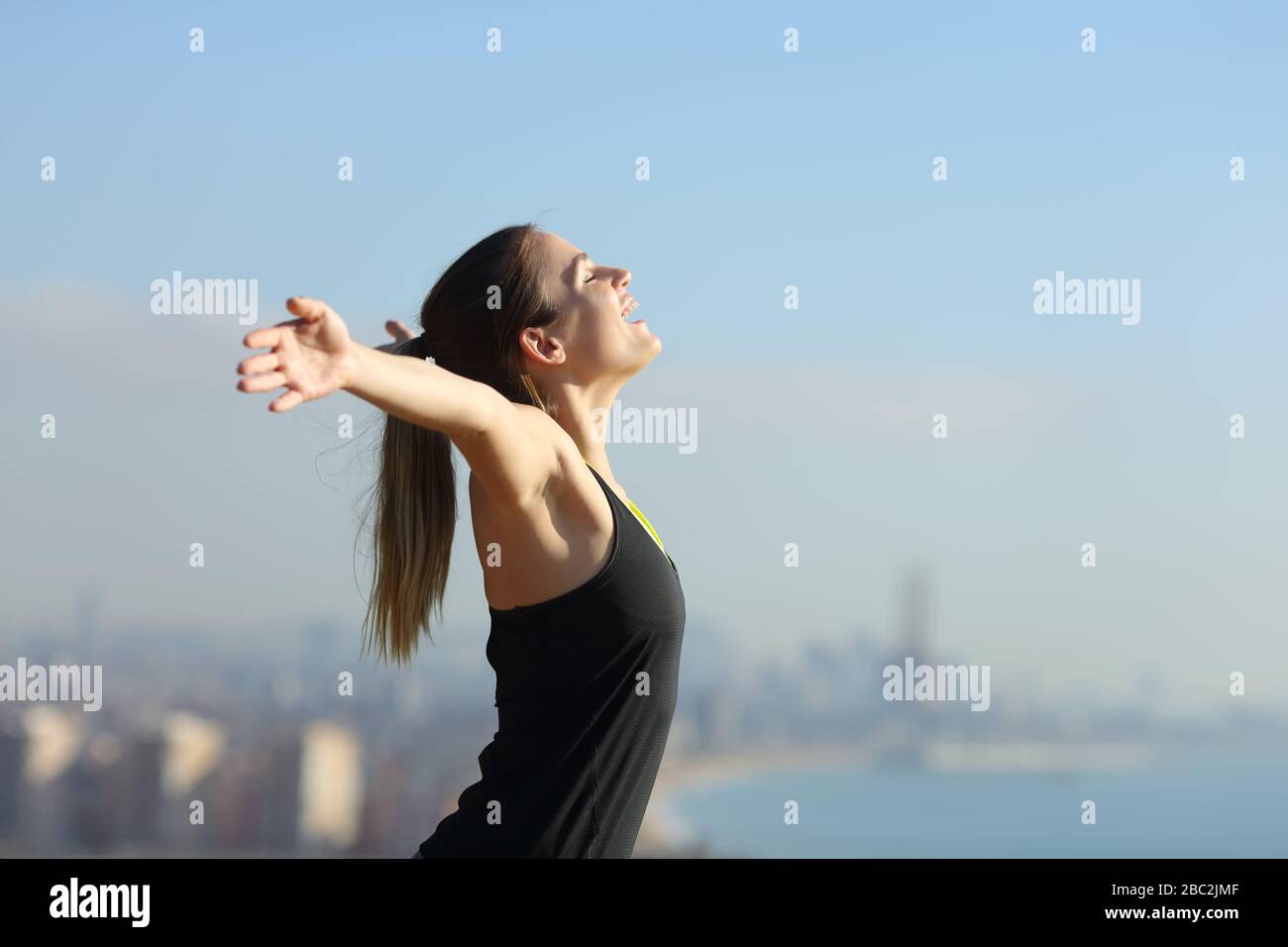 Seitenansicht eines aufgeregten Läufers, der im Freien in einem Stadtrand Erfolge feiert Stockfoto
