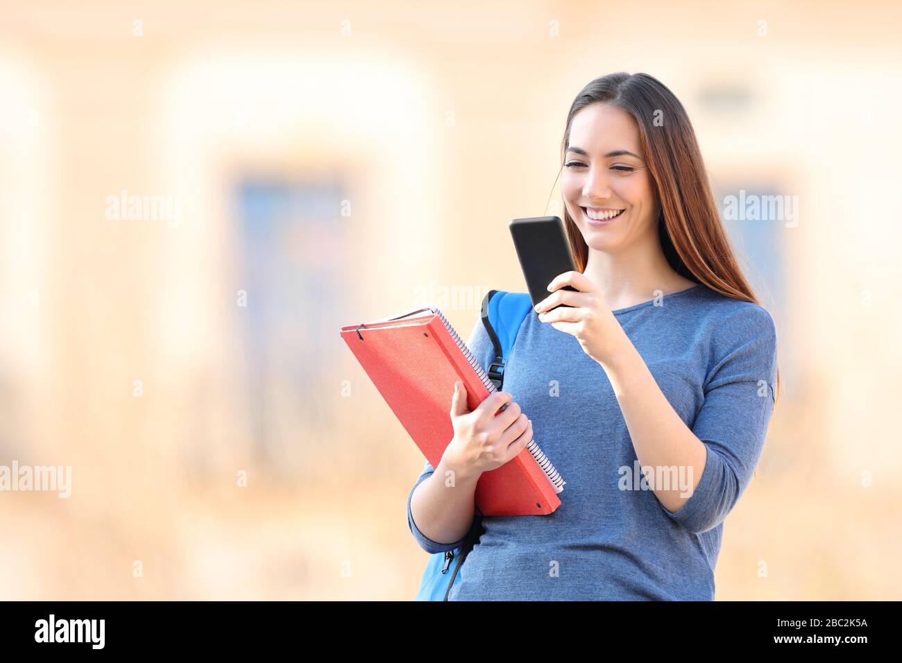 Zufriedene Studenten, die Online-Inhalte von Mobiltelefonen auf einem Campus abrufen Stockfoto