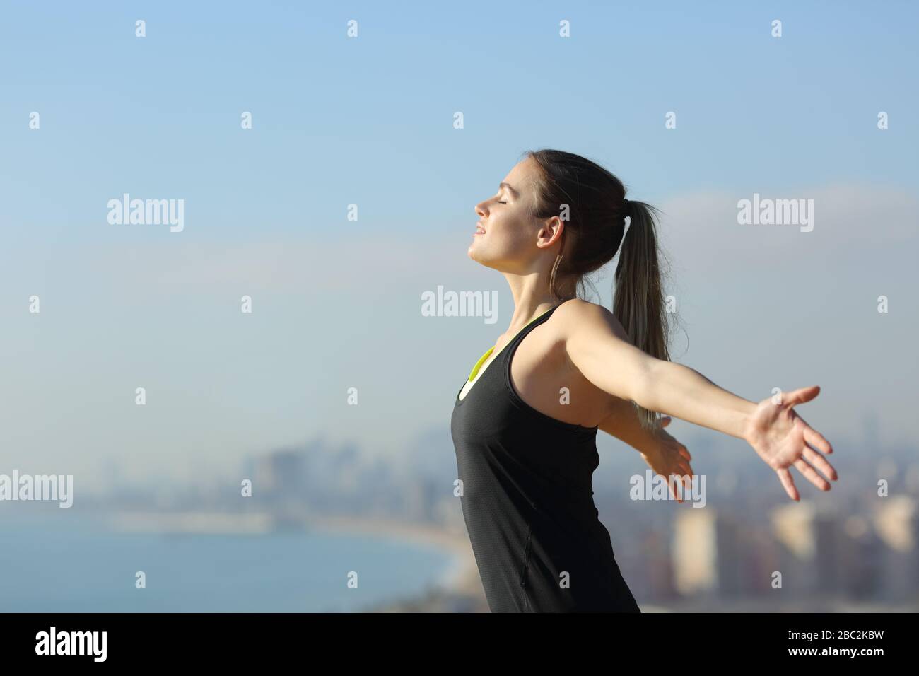 Seitenansicht Porträt eines entspannten Läufers, der an einem sonnigen Tag frische Luft in den Randgebieten der Stadt atmet Stockfoto