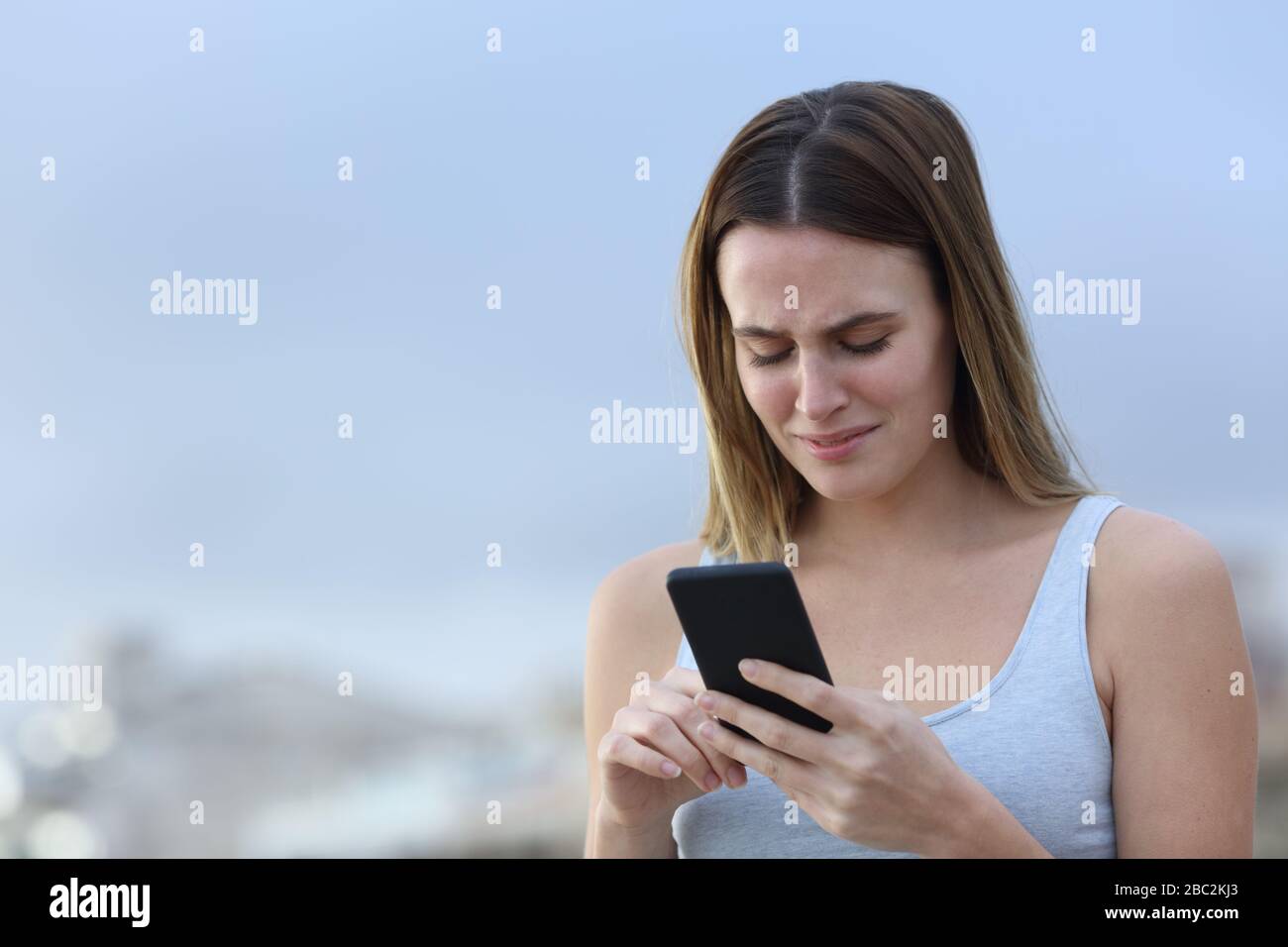 Trauriges Mädchen beschwert sich und schreit, das Smartphone auf der Straße zu überprüfen Stockfoto