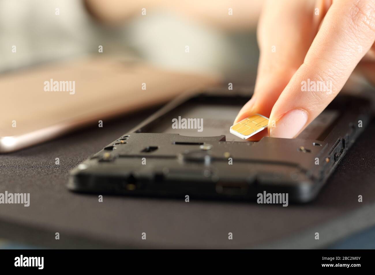 Nahaufnahme der Hände der Frau Einlegen der sim-Karte auf das Smartphone auf einem Schreibtisch Stockfoto