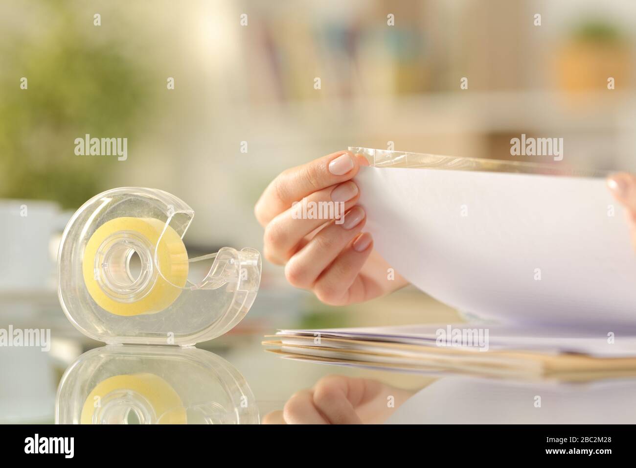 Nahaufnahme der Frau Hände Klebeband auf einem Papier auf einem Schreibtisch zu Hause kleben Stockfoto
