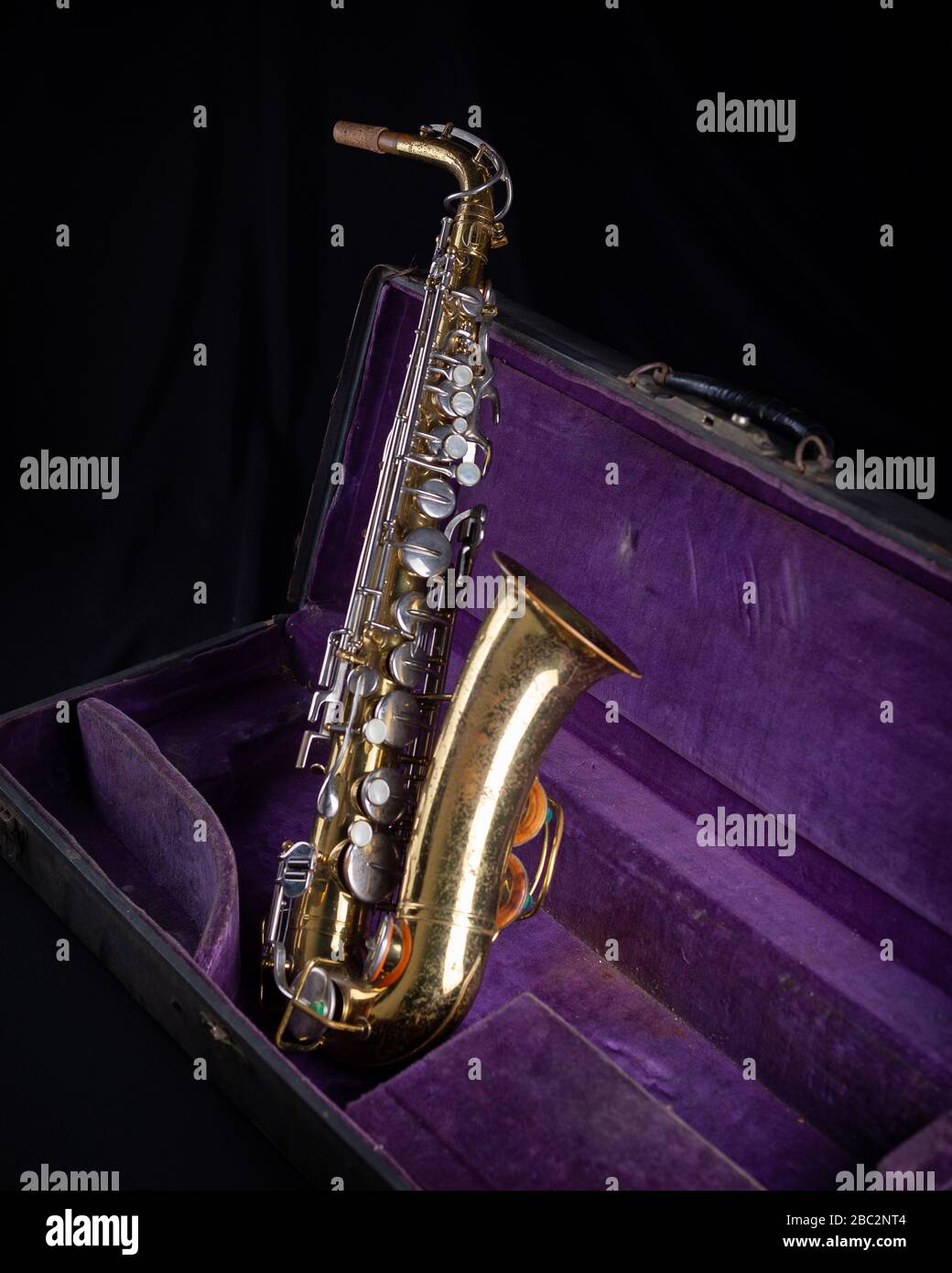 Buescher Alto Sax, Gold lackiert in Deep Purple Velvet-Lined Hartschalenkoffer Seite 1 auf schwarzem Hintergrund Stockfoto