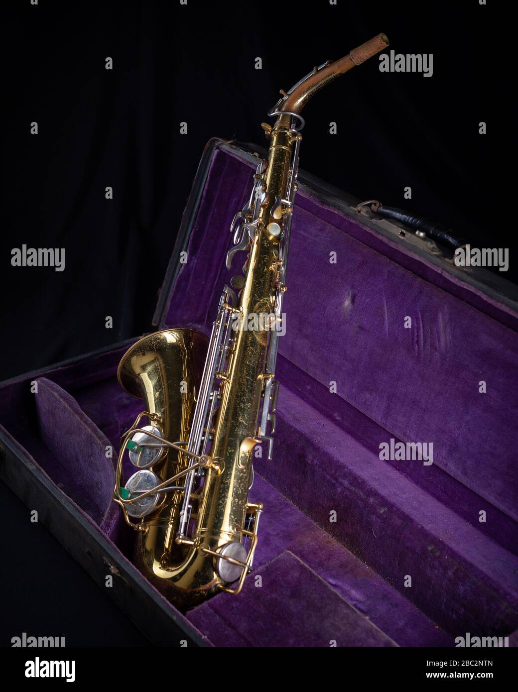 Buescher Alto Sax, Gold lackiert in Deep Purple Velvet-Lined Hartschalenkoffer Back 1 auf schwarzem Hintergrund Stockfoto