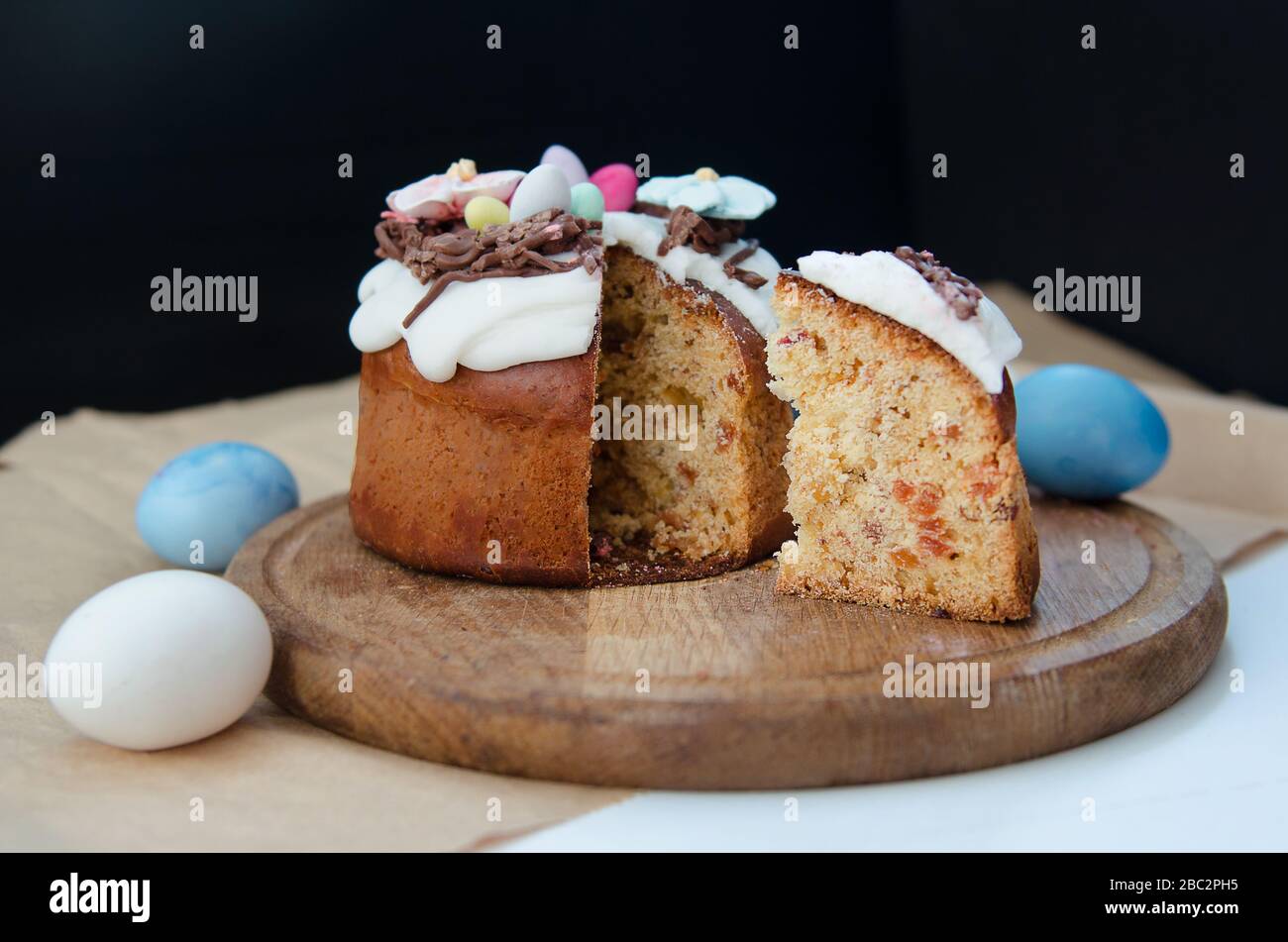 Festlicher Osterkuchen mit Blumenschmuck und gekucktem Stück Kuchen Stockfoto
