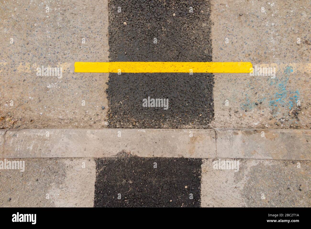 Eine sehr kurze Länge der neu lackierten Parksperrenbegrenzung der gelben Linie, bei der Straßenbauarbeiten die Oberfläche der Straßen in der Nähe der Bordsteinkante gestört haben. GROSSBRITANNIEN (116) Stockfoto