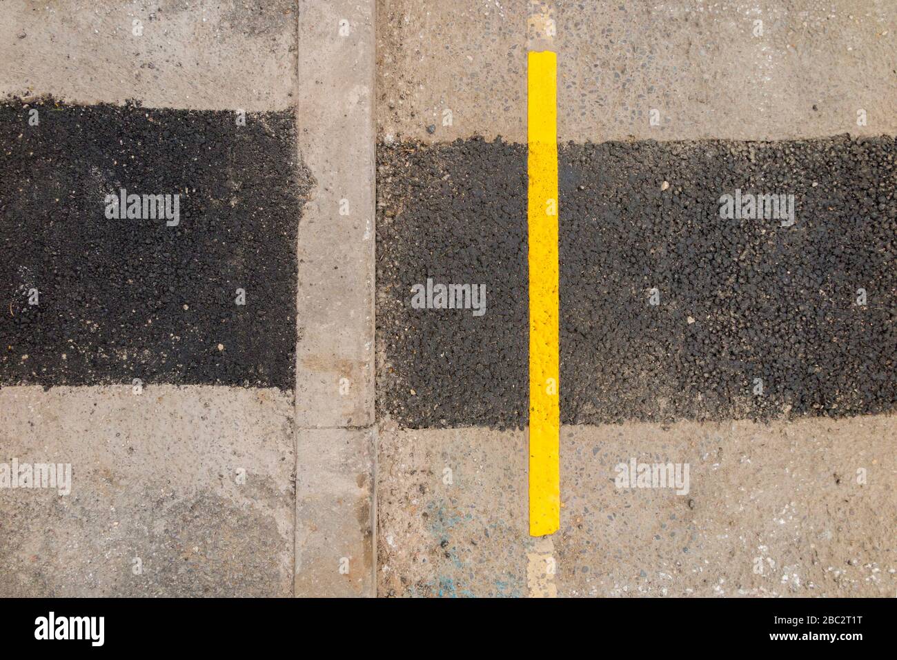 Eine sehr kurze Länge der neu lackierten Parksperrenbegrenzung der gelben Linie, bei der Straßenbauarbeiten die Oberfläche der Straßen in der Nähe der Bordsteinkante gestört haben. GROSSBRITANNIEN (116) Stockfoto