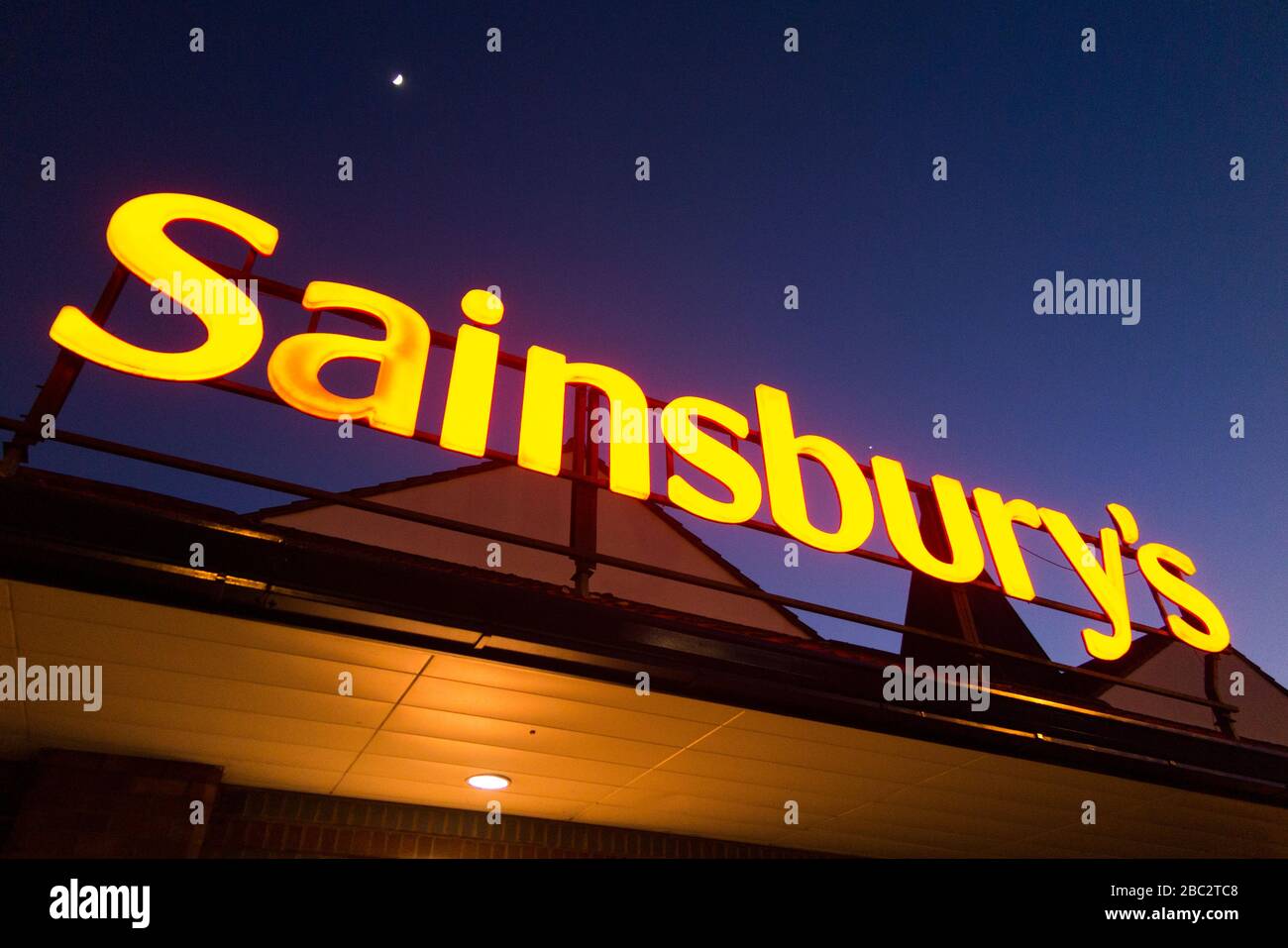 Sainsbury's Supermarkt-Schild nachts/abends mit hellblauem Nachthimmel, Mond und schwachen Sternen. GROSSBRITANNIEN (116) Stockfoto