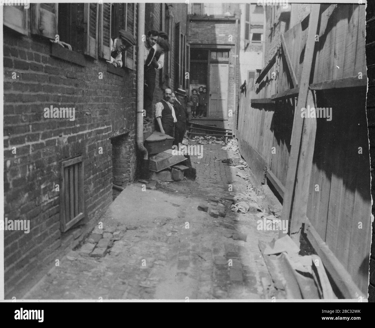 Gruppe von Mitarbeitern und mehreren kleinen Jungen in der überdachten Gasse Eingang zu einer Baltimore Garment Factory (3904010342). Stockfoto