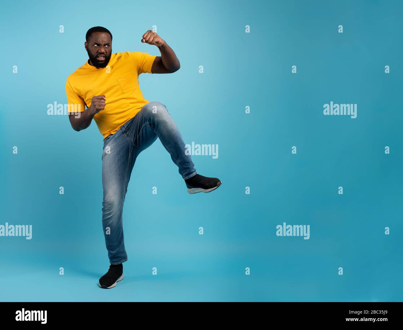 Der Mann ist wütend und kämpft mit Tritten. Blauer Hintergrund Stockfoto