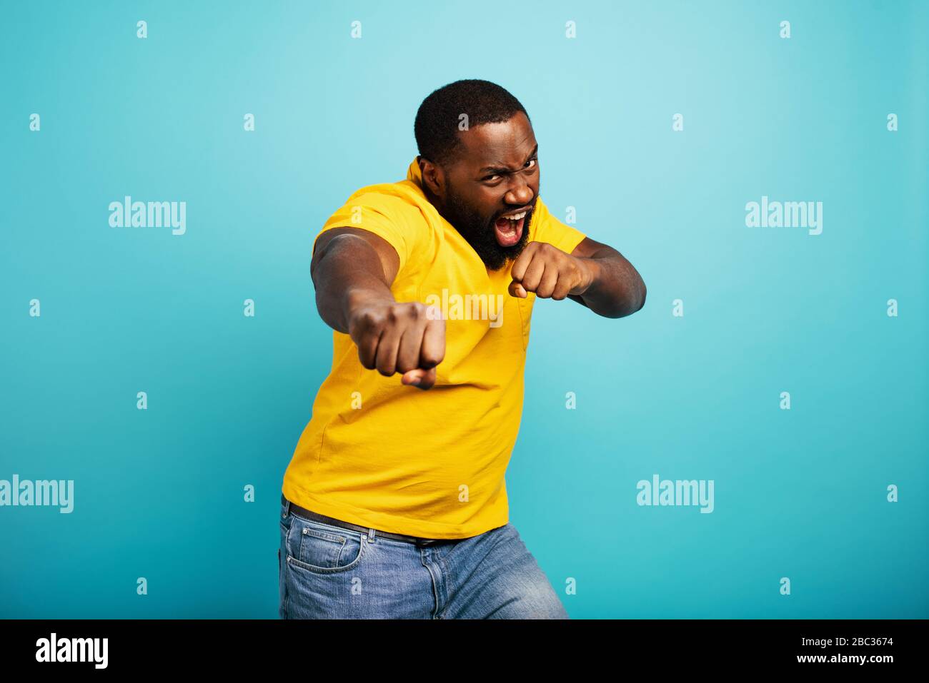 Der Mann ist wütend und kämpft mit Schlägen. Blauer Hintergrund Stockfoto