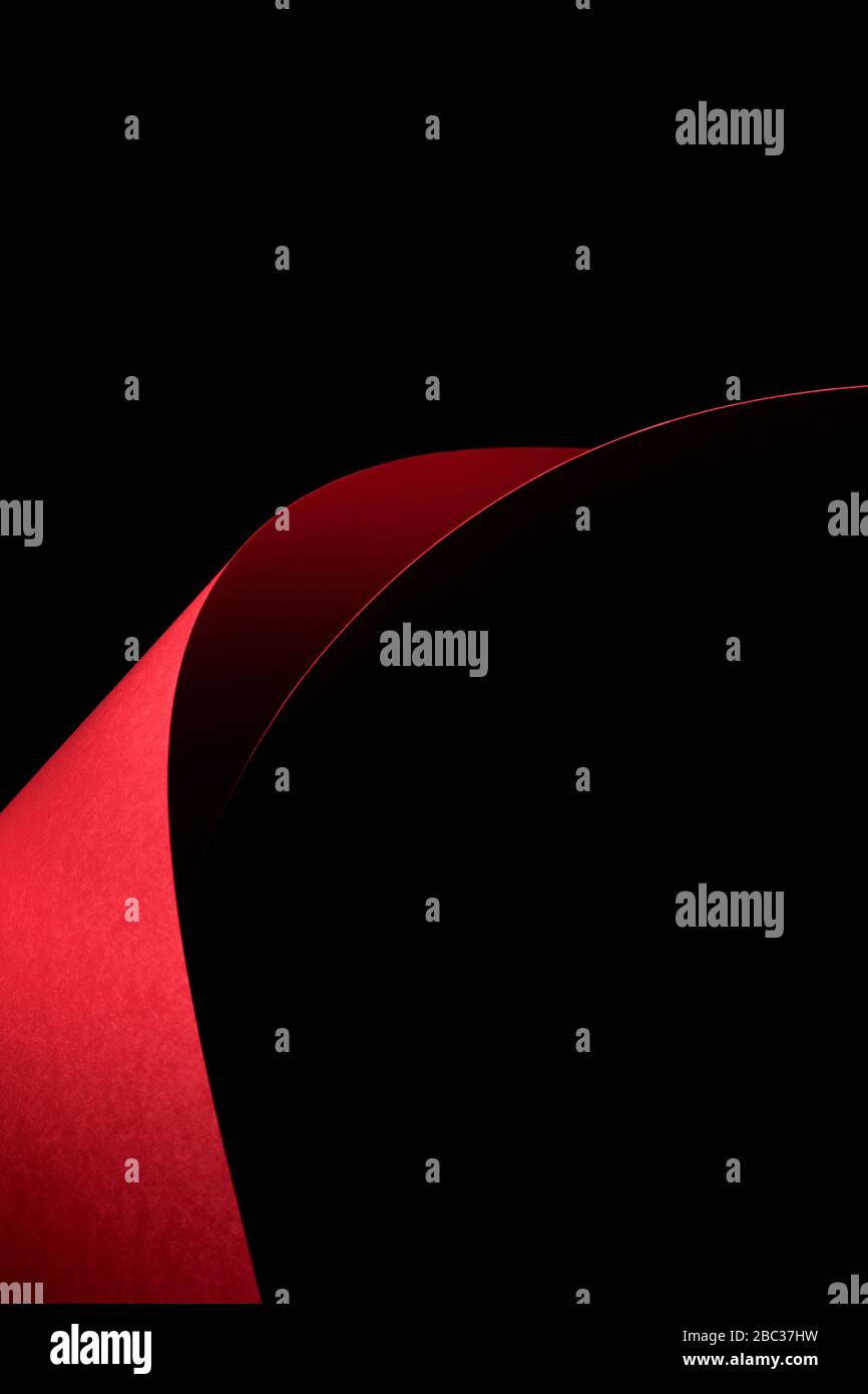 Zusammenfassung - Blätter mit rotem Papierrollen auf schwarzem Hintergrund. Einfaches, isoliertes Objekt mit Textraum, perfekt zur Veranschaulichung verschiedener Konzepte. Stockfoto