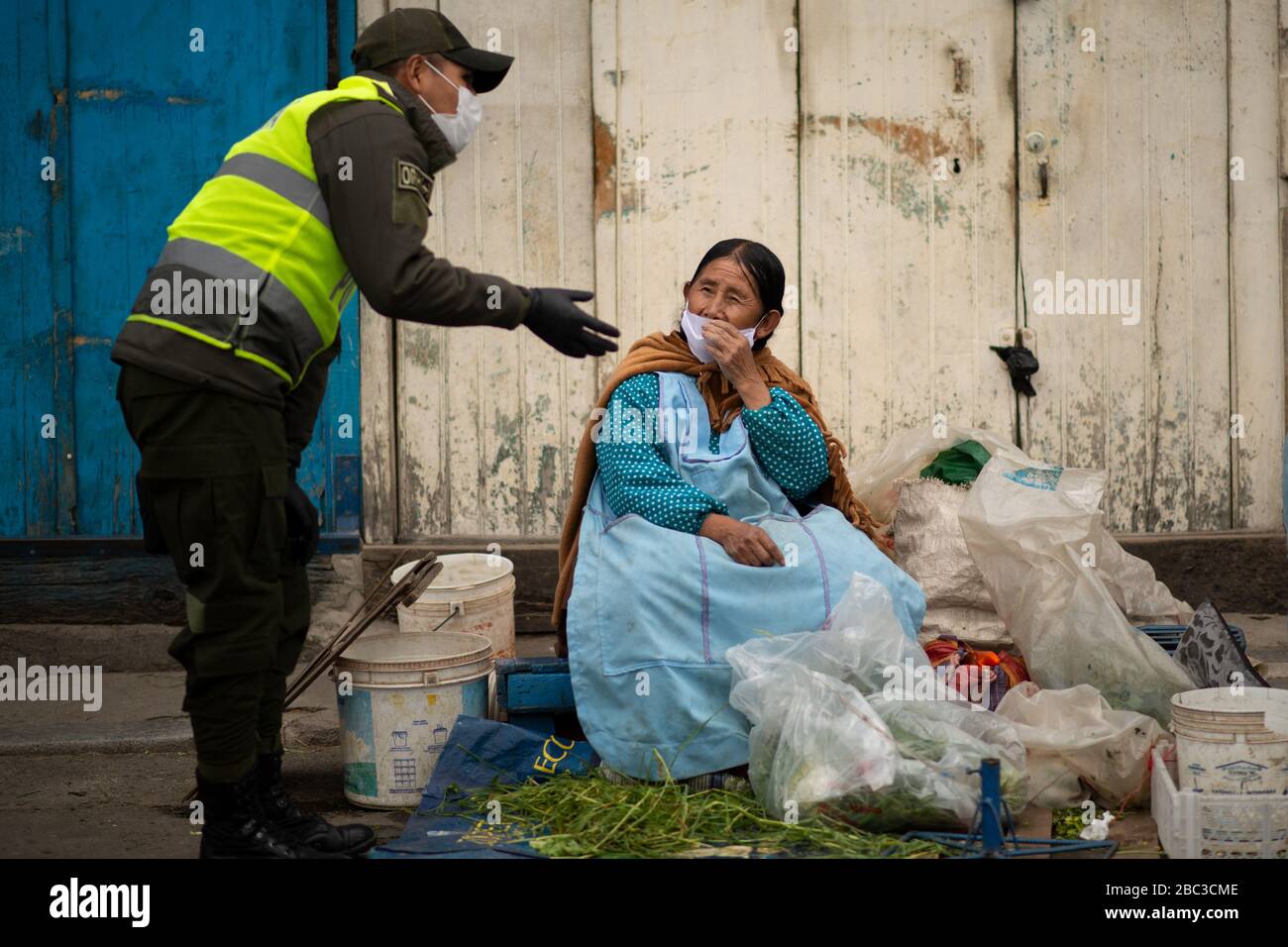 La Paz, Bolivien. März 2020. Ein Polizist erklärt einer alten Frau, die Lebensmittel auf dem Hauptmarkt von La Paz verkauft, die strengen Quarantänevorschriften. Stockfoto