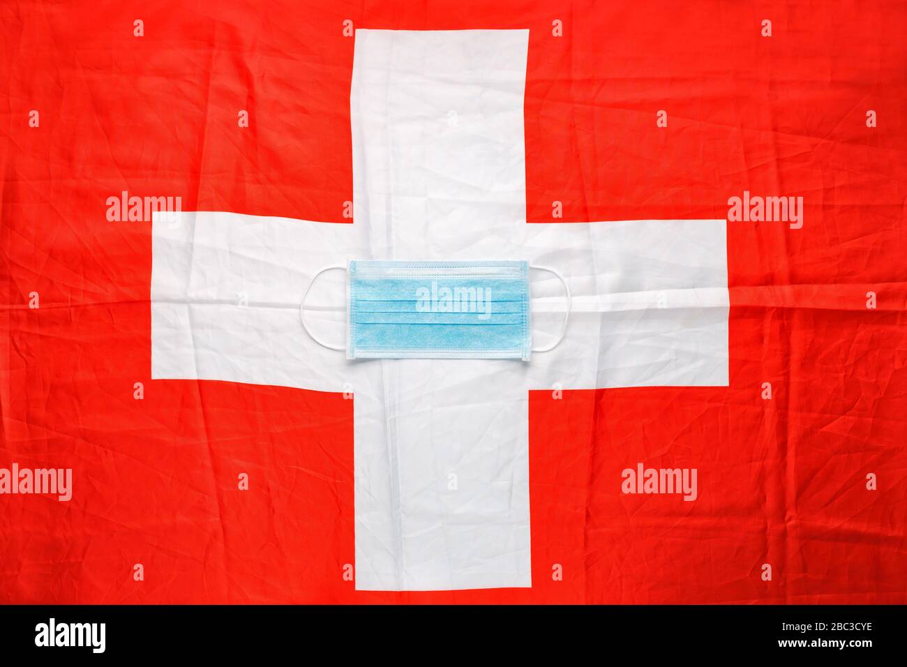 Coronavirus in der Schweiz. Schützende chirurgische Gesichtsmaske auf Schweizer Nationalflaggen. Schweizer Quarantäne, Schutzkoronavirus Symbol des Arztes, der Krankenschwester Stockfoto