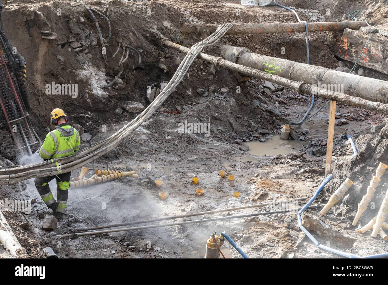 Die Straße wurde ausgegraben, um die Infrastruktur wie Wasserleitungen, Kanalisationsleitungen und Kabel neu zu entwickeln. Mann bei der Arbeit. Stockfoto
