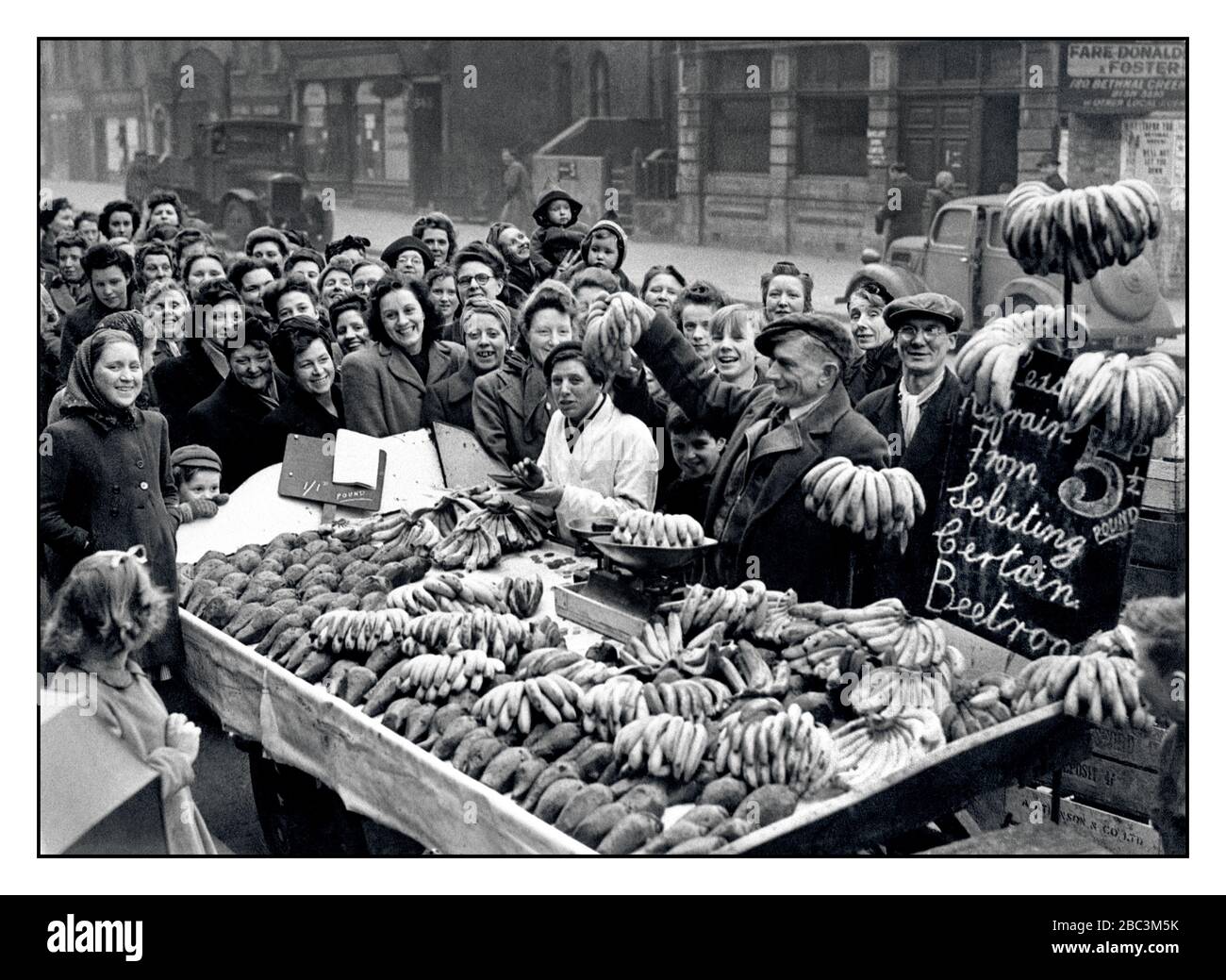 Vintage-Archiv 1940s Food Rationing Market Stall 1946 Post war WW2 Frische Bananen und Rote Beete werden in East End London verkauft, mit einer Menge sehr eifriger Kunden rund um den Stall Bethnal Green London UK Stockfoto