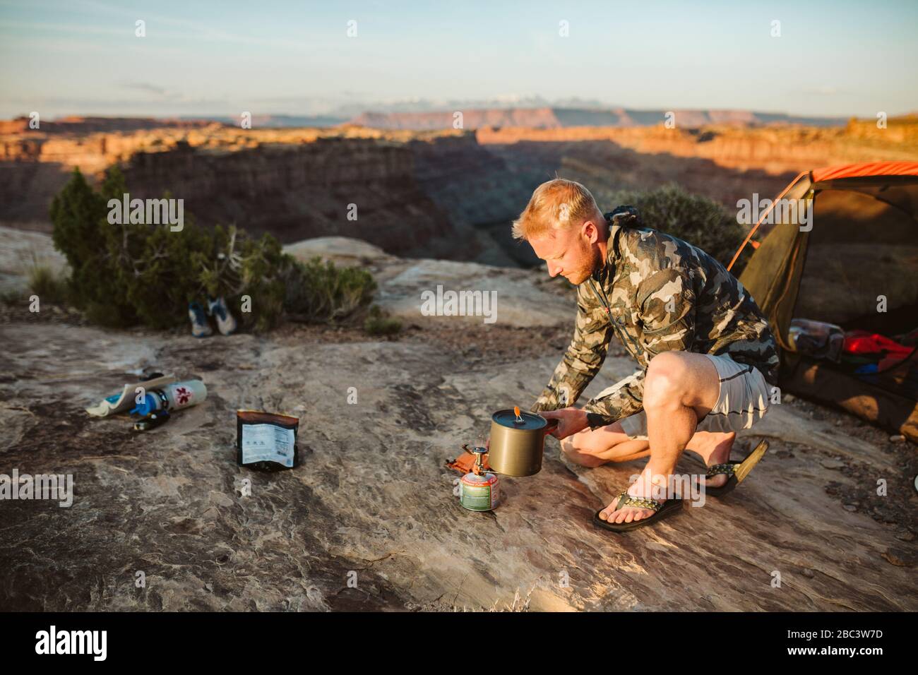 Männlicher Camper kocht Wasser mit einem Flüsterlicht im Camp in der Wüste Stockfoto