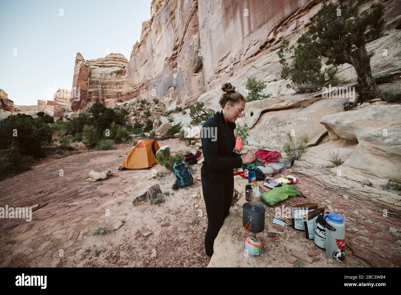 WanderFrau bereitet Abendessen während des abgelegenen Campens im Maze Utah zu Stockfoto